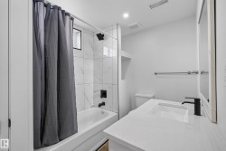Modern bathroom featuring a white vanity with an integrated sink, black single-handle faucet, and white countertop - 