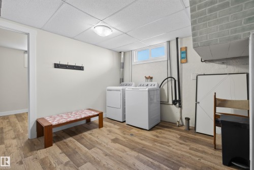 Dedicated laundry area featuring durable wood-finish flooring, a drop ceiling, and a high window for natural light - 14128 73 Street, Edmonton, AB 