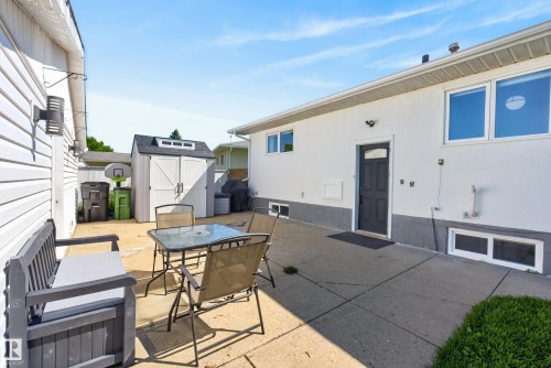 Concrete patio featuring a detached storage shed and a dark-paneled entry door - 14128 73 Street, Edmonton, AB 