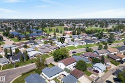 Aerial perspective of a residential neighborhood featuring detached homes with various roof styles and established landscaping - 