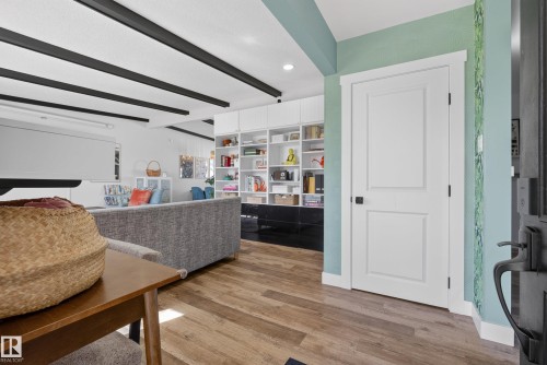 Open-concept living area featuring wood-finish flooring, exposed ceiling beams, and built-in shelving - 14128 73 Street, Edmonton, AB 