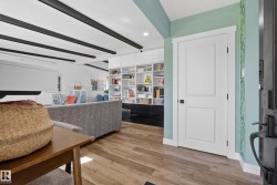 Open-concept living area featuring wood-finish flooring, exposed ceiling beams, and built-in shelving - 