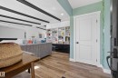 Open-concept living area featuring wood-finish flooring, exposed ceiling beams, and built-in shelving - 14128 73 Street, Edmonton, AB 