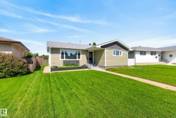 Ranch-style exterior featuring light green siding, a contrasting dark gray gable, a dark asphalt shingle roof, and a black front door - 