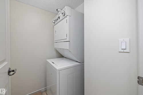 Dedicated laundry area featuring a stacked washer and dryer unit - 101 13825 155 Avenue, Edmonton, AB 