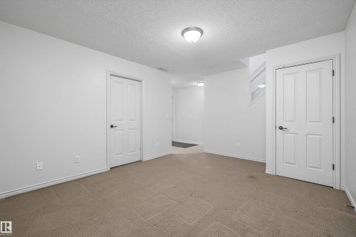 Versatile room featuring two paneled doors, neutral carpeting, and white walls - 101 13825 155 Avenue, Edmonton, AB 