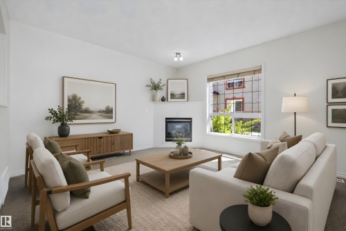 Bright living area featuring a corner fireplace, large window with blinds, and white painted walls - 101 13825 155 Avenue, Edmonton, AB 