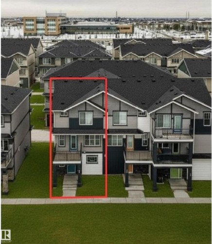 Three-story townhome featuring a multi-tone facade with dark grey siding, light grey shingle siding, and white trim accents - 96 1530 Tamarack Boulevard, Edmonton, AB 