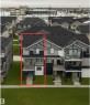 Three-story townhome featuring a multi-tone facade with dark grey siding, light grey shingle siding, and white trim accents - 96 1530 Tamarack Boulevard, Edmonton, AB 
