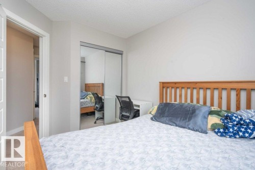 Bedroom featuring light gray walls, carpet flooring, and a mirrored sliding closet door - 96 1530 Tamarack Boulevard, Edmonton, AB 