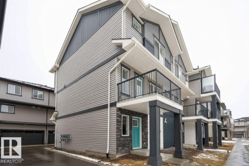 Modern multi-story facade featuring light grey siding, dark grey accent siding, and stone veneer detailing - 96 1530 Tamarack Boulevard, Edmonton, AB 
