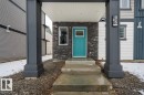 Entryway featuring a vibrant turquoise door, stacked stone facade, and concrete steps - 96 1530 Tamarack Boulevard, Edmonton, AB 