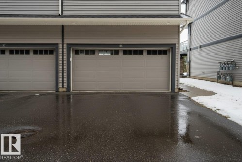 Two garage doors featuring upper window panels and dark trim - 96 1530 Tamarack Boulevard, Edmonton, AB 