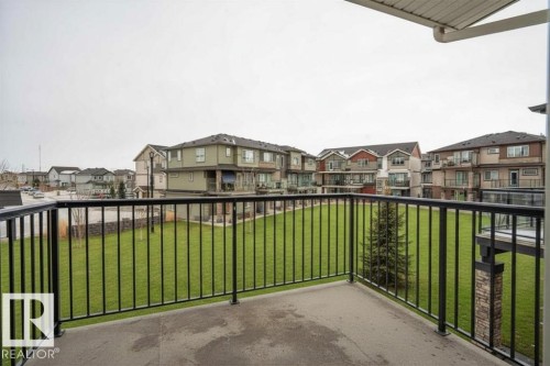 Private concrete balcony with black metal railings overlooking a landscaped green space - 96 1530 Tamarack Boulevard, Edmonton, AB 