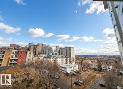 Cityscape featuring a mix of high-rise and mid-rise buildings, residential structures, and distant tree lines under a partly cloudy sky - 