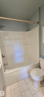 Bathroom featuring a white integrated shower/tub unit with a jetted tub, chrome fixtures, and light gray wall paint - 