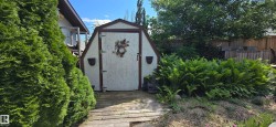 Gable-roof storage shed with an artistic door decal and twin exterior planters - 