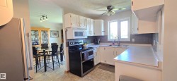 Kitchen featuring white cabinetry, light-toned countertops, tile flooring, and a stainless steel over-the-range microwave - 