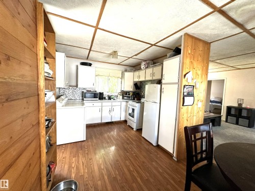 Kitchen with wood-finish flooring, white cabinetry, and a patterned tile backsplash - 825 2 Street, Thorhild, AB 