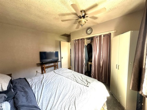 Ceiling fan with light fixture, textured ceiling, solid door, and built-in closet with privacy drapes - 825 2 Street, Thorhild, AB 
