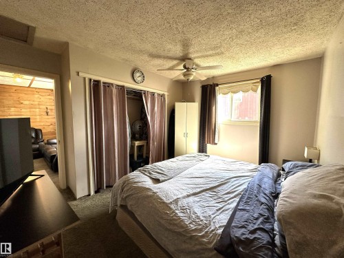 Carpeted room featuring a ceiling fan, window with valance, and a recessed closet with privacy curtains - 825 2 Street, Thorhild, AB 