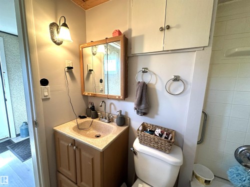 Bathroom vanity featuring an integrated sink, wood-finish cabinetry, and a mirrored medicine cabinet - 825 2 Street, Thorhild, AB 