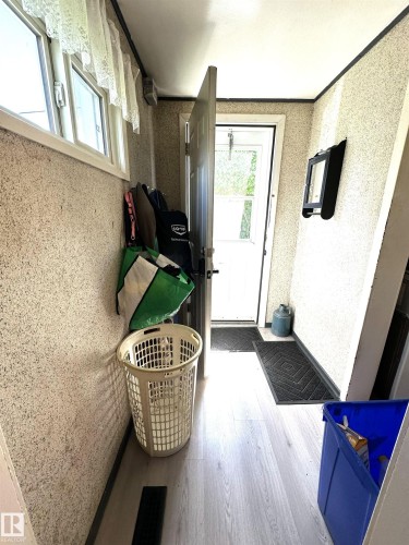 Entryway featuring light wood-finish flooring, a white trim window, and a white interior door - 825 2 Street, Thorhild, AB 