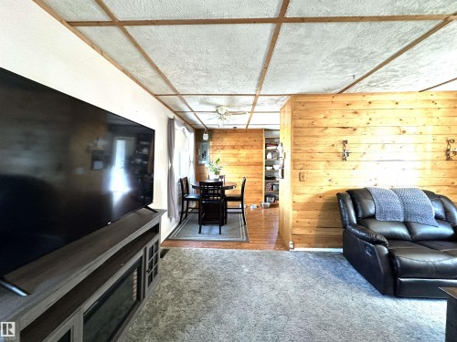 Room featuring wood-finish wall paneling and a textured ceiling with wood-finish beams - 825 2 Street, Thorhild, AB 