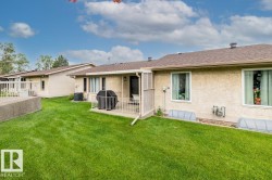 Expansive green lawn with a private patio featuring a white metal railing - 