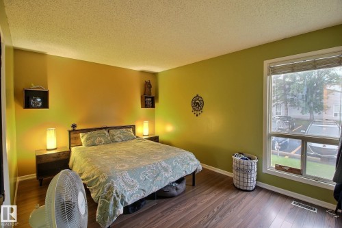 Bedroom featuring wood-finish flooring and a large window with horizontal blinds - 30 14620 26 Street, Edmonton, AB 