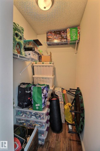 Utility closet featuring wire shelving, wood-finish flooring, textured ceiling, and a flush-mount ceiling light fixture - 30 14620 26 Street, Edmonton, AB 