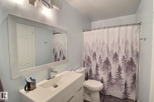 Modern vanity featuring an integrated sink with a chrome faucet, under-sink cabinetry, and a large framed mirror - 30 14620 26 Street, Edmonton, AB 