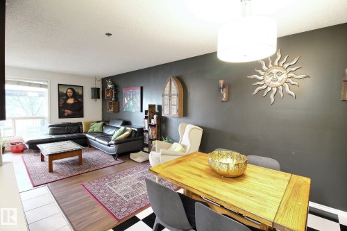 Open-concept living and dining area featuring wood-finish flooring, a neutral ceiling, and a prominent window - 30 14620 26 Street, Edmonton, AB 