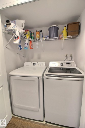 Dedicated laundry area featuring a white front-load dryer, a white top-load washing machine, and wall-mounted wire shelving - 30 14620 26 Street, Edmonton, AB 