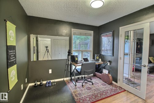 Office space featuring a window, built-in overhead lighting, French-style paneled door, and wood-finish flooring - 30 14620 26 Street, Edmonton, AB 