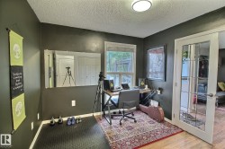 Office space featuring a window, built-in overhead lighting, French-style paneled door, and wood-finish flooring - 