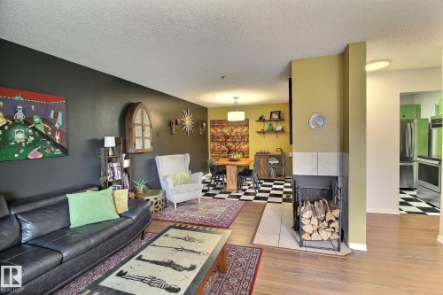 Living area featuring light wood-finish flooring and a tiled fireplace surround - 30 14620 26 Street, Edmonton, AB 