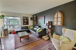 Living area featuring wood-finish flooring, a large window, a dark accent wall, and recessed ceiling fixtures - 