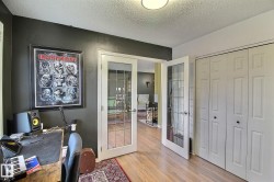 Room featuring wood-finish flooring, a pair of bi-fold closet doors with black hardware, and double French doors with clear glass panes - 