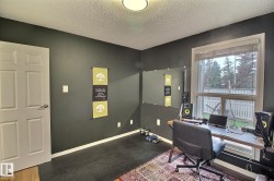 Room featuring a large window with privacy blinds, dark wall paint, textured ceiling, a flush mount ceiling light, and a white interior door - 