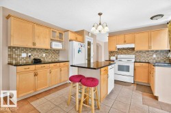 Kitchen featuring light wood-finish cabinetry, dark countertops, and a mosaic tile backsplash - 
