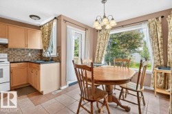 Kitchen and dining area featuring tile flooring, light wood-finish cabinetry, a tiled backsplash, and a contemporary pendant light fixture - 