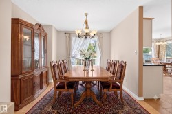 Formal dining area featuring a chandelier, light wood-finish flooring, and a balcony with white railings - 