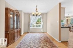 Spacious interior room featuring light wood-finish flooring, a central window with white trim, and a decorative chandelier - 