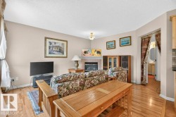 Living area with wood-finish flooring, a fireplace with a stone surround, and light-toned walls - 