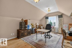 Attic room featuring a window with natural light, sloped ceilings, hardwood flooring, and a decorative area rug - 