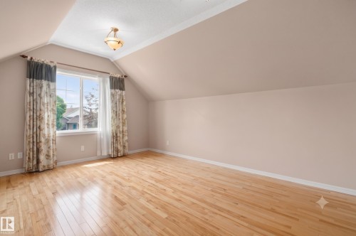 Spacious room featuring hardwood flooring, sloped ceilings, and a large multi-pane window - 572 Byrne Crescent, Edmonton, AB 