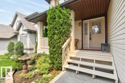 Welcoming front entry featuring light-colored siding, a covered porch with white columns, and a decorative glass front door - 