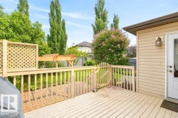 Rear outdoor wooden deck with a privacy lattice panel, a coordinating wooden pergola, and a small wooden gate - 