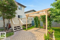 Rear yard featuring a wooden deck with stairs, a paved patio area, and a timber pergola - 